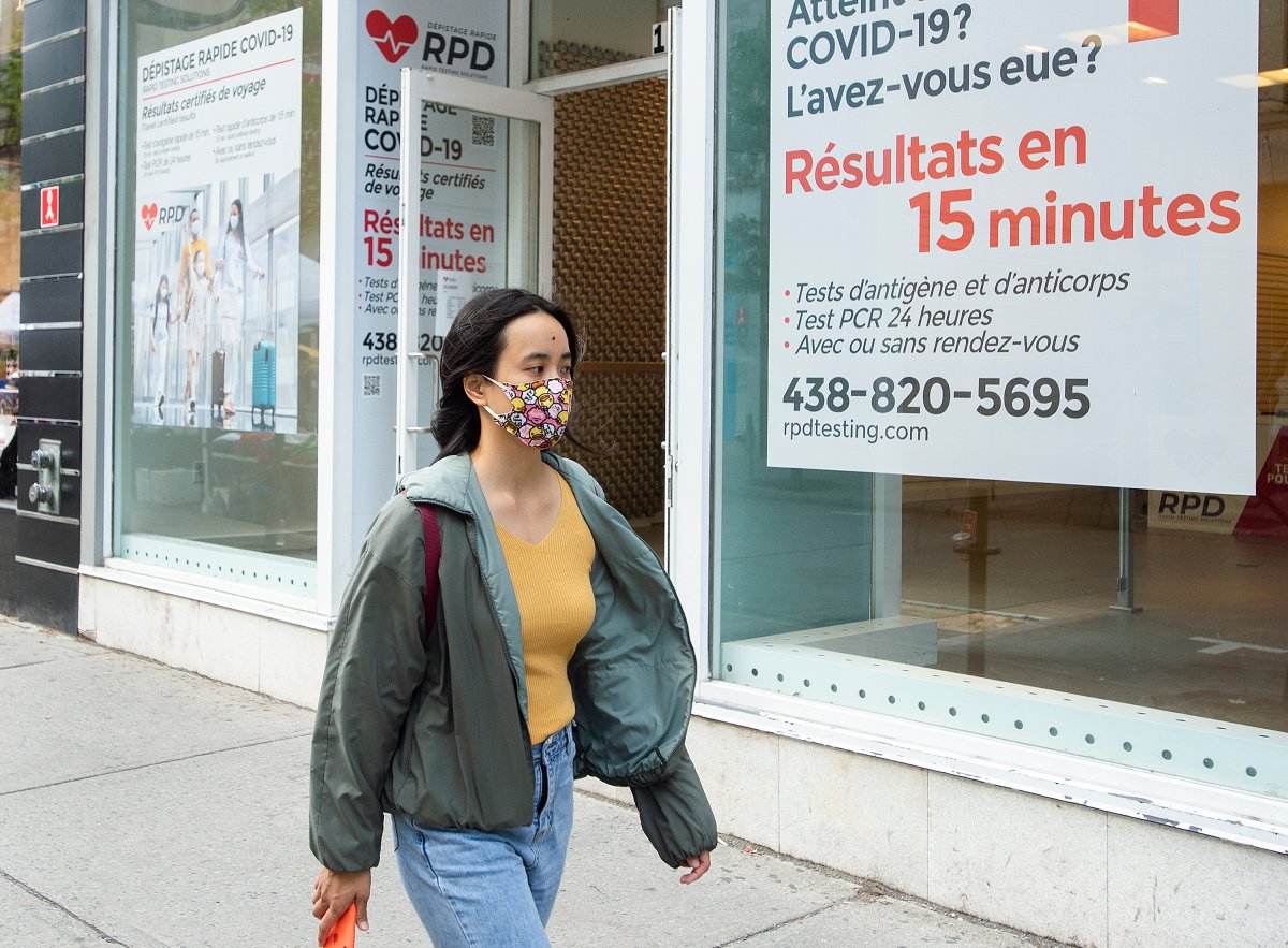 A woman wears a face mask as she walks by a COVID-19 rapid testing clinic in Montreal, Sunday, September 12, 2021, as the COVID-19 pandemic continues in Canada and around the world.