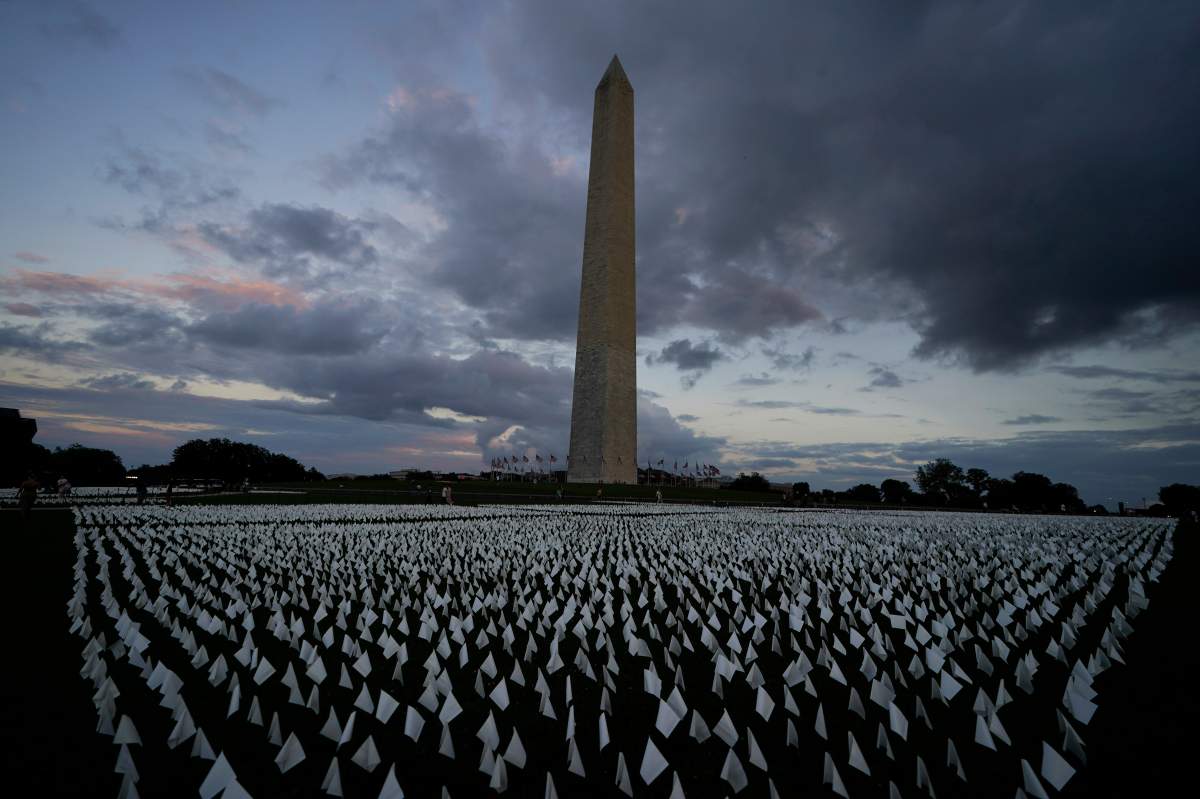 With the Washington Monument in the background, people look at white flags that are part of artist Suzanne Brennan Firstenberg’s temporary art installation, “In America: Remember,” in remembrance of Americans who have died of COVID-19, on the National Mall in Washington, Friday, Sept. 17, 2021. The installation consists of more than 630,000 flags. (AP Photo/Brynn Anderson)