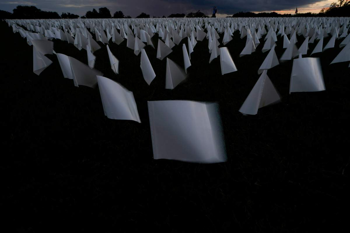 As the sunsets white flags are displayed as part of artist Suzanne Brennan Firstenberg’s temporary art installation, “In America: Remember,” in remembrance of Americans who have died of COVID-19, on the National Mall in Washington, Friday, Sept. 17, 2021. The installation consists of more than 630,000 flags. (AP Photo/Brynn Anderson)