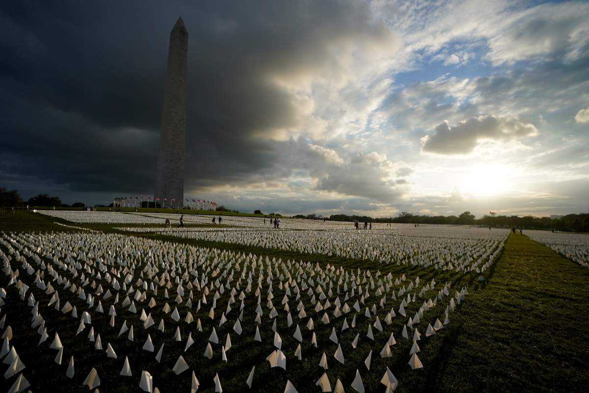 With the Washington Monument in the background, people look at white flags that are part of artist Suzanne Brennan Firstenberg’s temporary art installation, “In America: Remember,” in remembrance of Americans who have died of COVID-19, on the National Mall in Washington, Friday, Sept. 17, 2021. The installation consists of more than 630,000 flags. (AP Photo/Brynn Anderson)