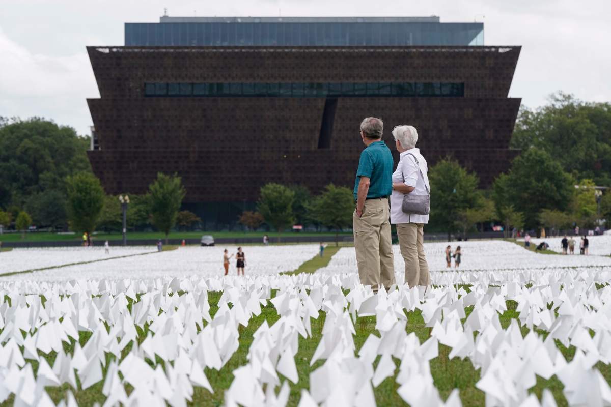 Visitors look out at artist Suzanne Brennan Firstenberg’s “In America: Remember,” a temporary art installation made up of white flags to commemorate Americans who have died of COVID-19, on the National Mall in Washington, Tuesday, Sept. 21, 2021. (AP Photo/Patrick Semansky)