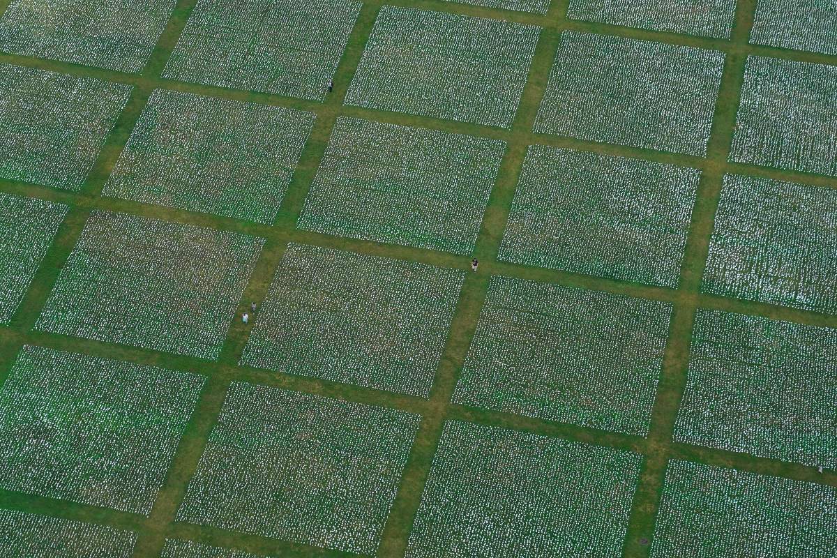 People visit artist Suzanne Brennan Firstenberg’s “In America: Remember,” a temporary art installation made up of white flags to commemorate Americans who have died of COVID-19, on the National Mall in Washington, Wednesday, Sept. 22, 2021. (AP Photo/Patrick Semansky)