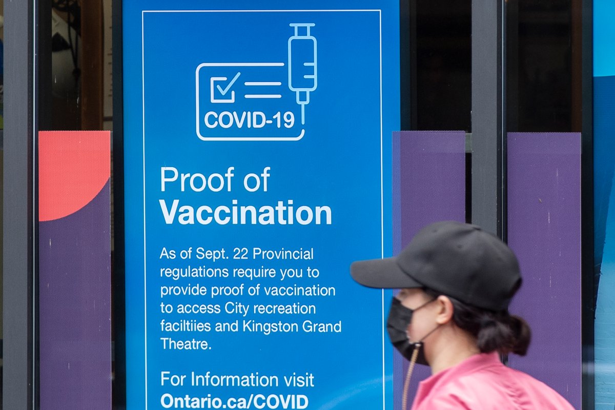 A person wears a mask to protect them from the COVID-19 virus while walking past information about vaccination proof in Kingston, Ontario on Thursday September 23, 2021. THE CANADIAN PRESS IMAGES/Lars Hagberg.