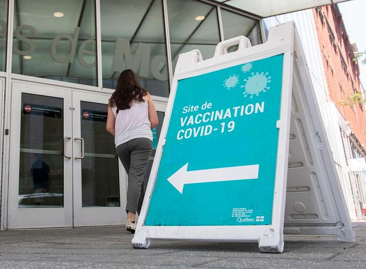 People are shown next to a COVID-19 vaccination sign in Montreal, Saturday,  August 21, 2021, as the COVID-19 pandemic continues in Canada and around the world. 