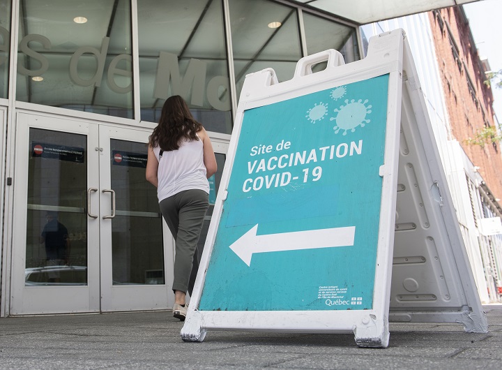 People are shown next to a COVID-19 vaccination sign in Montreal, Saturday,  August 21, 2021, as the COVID-19 pandemic continues in Canada and around the world. 