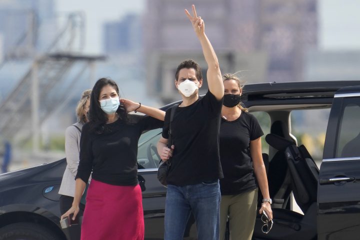Michael Kovrig, centre right, waves to media with his wife Vina Nadjibulla, centre left, and sister Ariana Botha after his arrival at Pearson International Airport in Toronto, Saturday, Sept. 25, 2021.