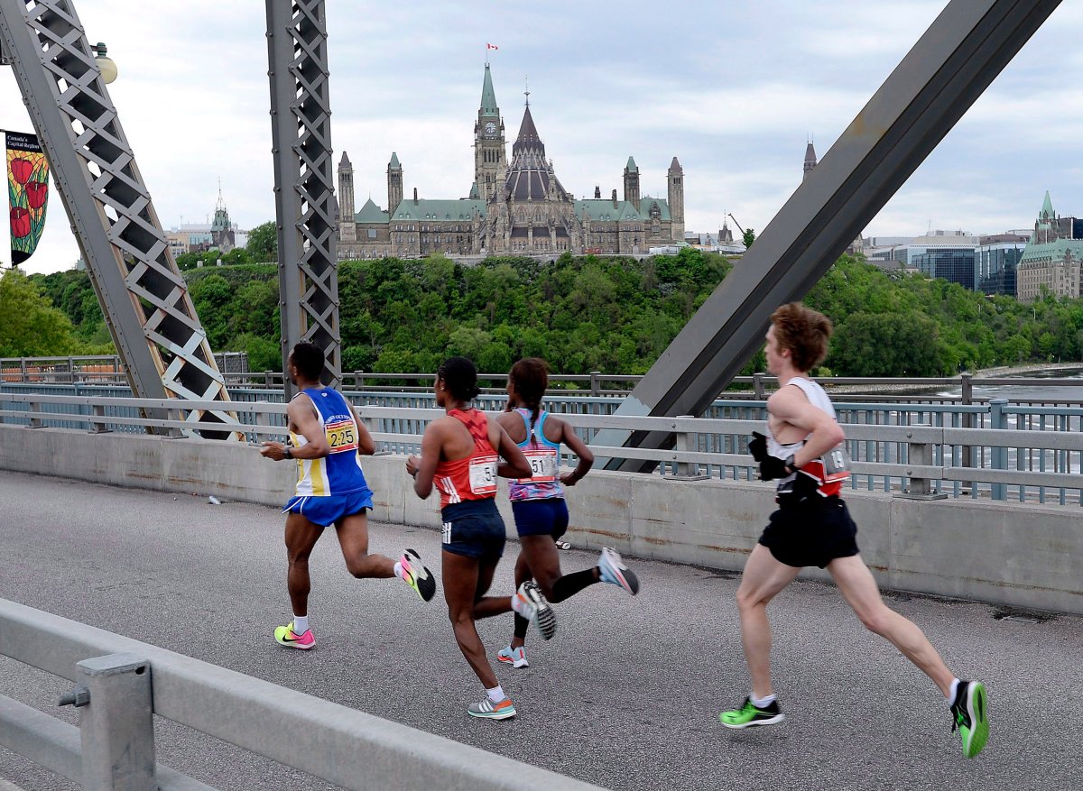 A pace runner leads Hiwot Gebrekidan of Ethiopia, second from left, Gelete Burka of Ethiopia, and Lucas McAneney of Canada across the Alexandra Bridge in front of Parliament Hill during the Ottawa Marathon in Ottawa on Sunday, May 27, 2018. Ottawa Race Weekend is set for an in-person return in 2022.