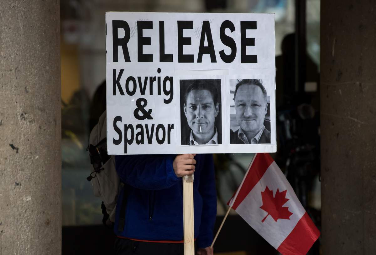 A young man holds a sign bearing photographs of Michael Kovrig and Michael Spavor, who have been detained in China for more than a year, outside B.C. Supreme Court where Huawei chief financial officer Meng Wanzhou was attending a hearing, in Vancouver, on Tuesday, Jan. 21, 2020. THE CANADIAN PRESS/Darryl Dyck