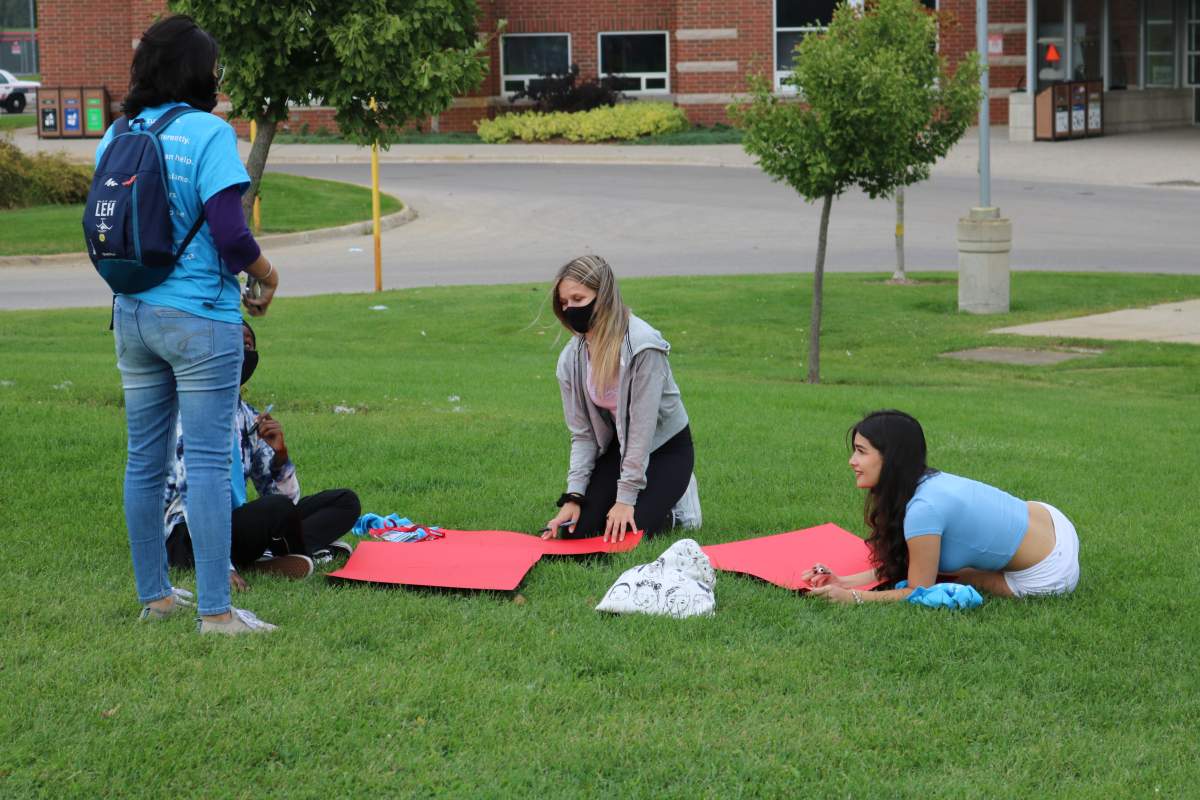 Four Fanshawe students decorating signs to protest sexual and gender based violence on campus on Sep. 20, 2021
