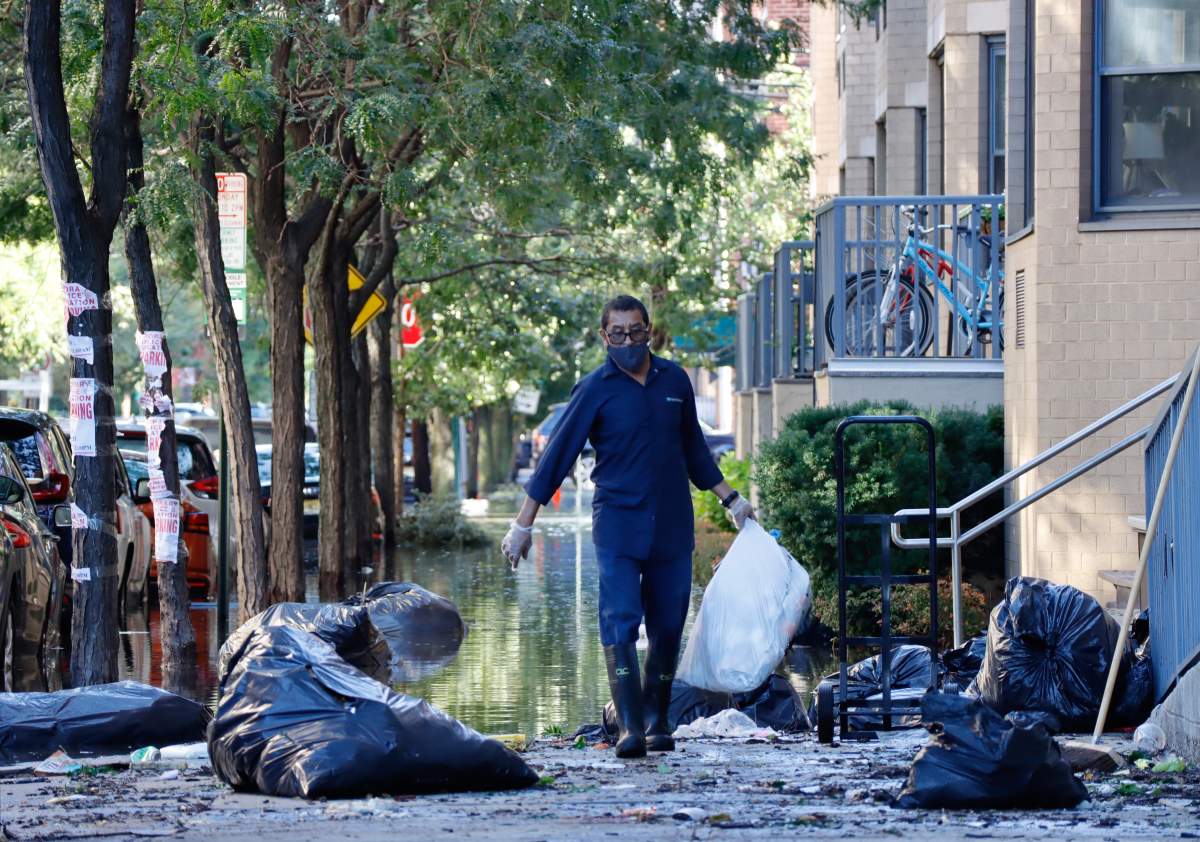 HOBOKEN, NJ – SEPTEMBER 2: A man cleans up garbage from a flooded street the morning after the remnants of Hurricane Ida drenched the New York City and New Jersey area on September 2, 2021 in Hoboken, New Jersey. (Photo by Gary Hershorn/Getty Images)