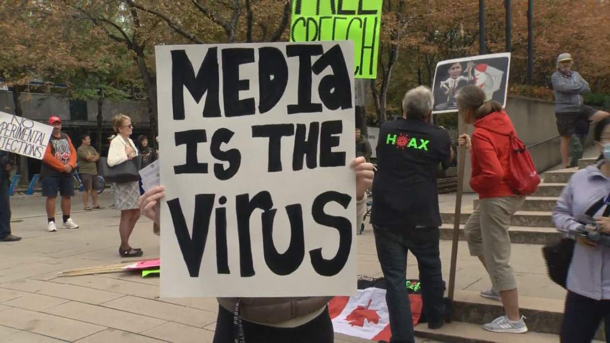 A woman holds up a sign reading ‘Media is the Virus’ outside B.C.’s Supreme Court Monday morning.