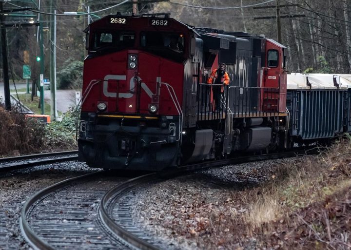 A CN rail worker stands on an idle locomotive as protesters opposed to the Trans Mountain pipeline expansion block rail lines, in Burnaby, B.C., on Friday, November 27, 2020.