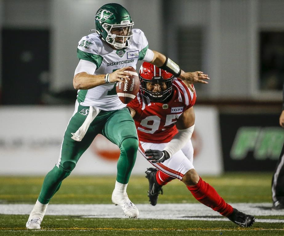 Saskatchewan Roughriders quarterback Cody Fajardo, left, is sacked by Calgary Stampeders' Stefen Banks during first half CFL football action in Calgary, Saturday, Oct. 23, 2021.THE CANADIAN PRESS/Jeff McIntosh.