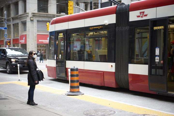 A woman wearing a protective face mask waits for the streetcar in the financial district in Toronto, Ont., on Nov. 3, 2020, amid the ongoing COVID-19 pandemic. 
