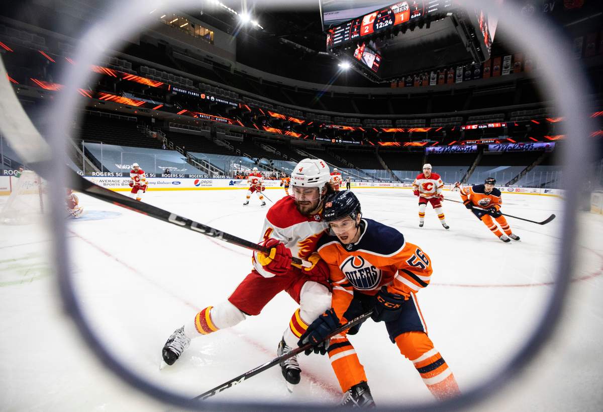 Edmonton Oilers' Kailer Yamamoto (56) and Calgary Flames' Rasmus Andersson (4) battle for the puck during second period NHL action in Edmonton on Friday, April 2, 2021.