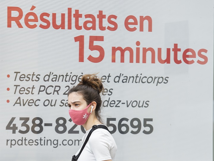 A woman wears a face mask as she walks by a COVID-19 rapid testing business in Montreal, Sunday, September 12, 2021, as the COVID-19 pandemic continues in Canada and around the world. 