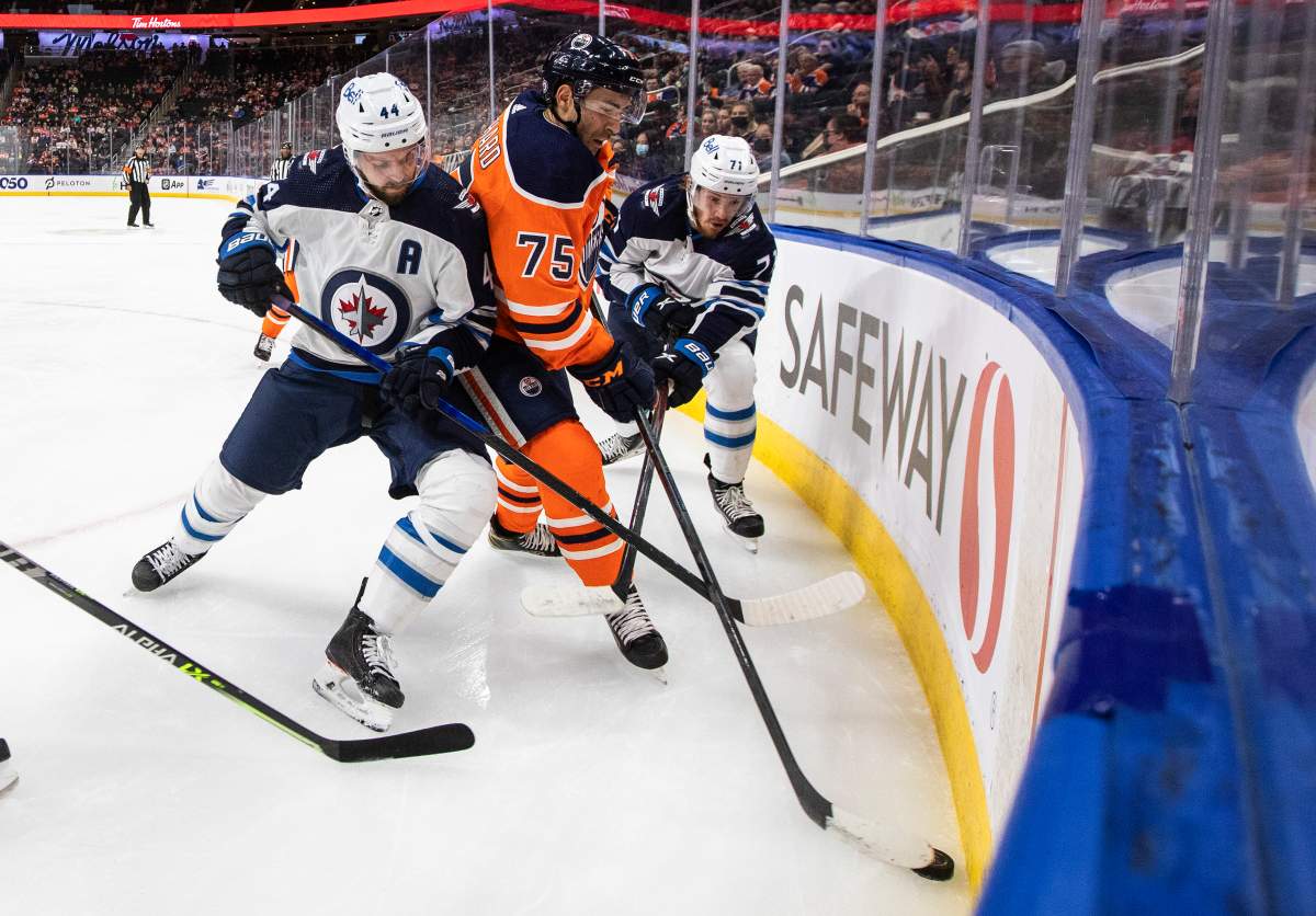 Winnipeg Jets’ Josh Morrissey (44) and Evgeny Svechnikov (71) battle for the puck with Edmonton Oilers Evan Bouchard (75) during first-period NHL pre-season action in Edmonton on Saturday, Oct. 2, 2021.