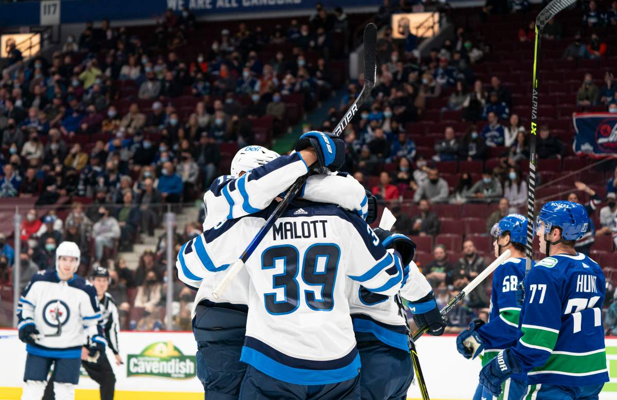 Winnipeg Jets’ Jeff Malott is congratulated by teammates after scoring a goal against the Vancouver Canucks during first period NHL pre-season hockey action in Vancouver, Sunday, Oct. 3, 2021.