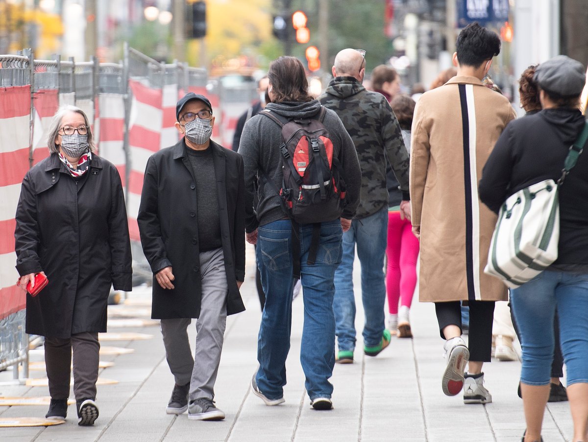 People wear face masks a they walk along a street in Montreal, Sunday, October 10, 2021, as the COVID-19 pandemic continues in Canada and around the world. 