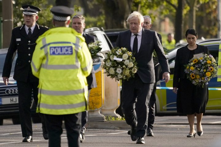 British Prime Minister Boris Johnson, followed by Home Secretary Priti Patel, right, and flanked by Leader of the Labour Party Keir Starmer, second from left, carry flowers as they arrive at the scene where a member of Parliament was stabbed Friday, in Leigh-on-Sea, Essex, England, Saturday, Oct. 16, 2021.