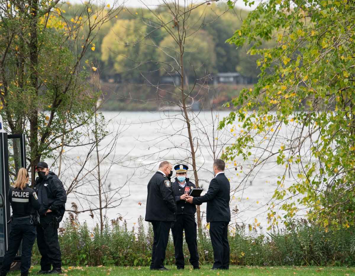 Investigators stand on the shoreline of the St.Lawrence River, Monday, October 18, 2021 where a firefighter drowned during a rescue operation in Montreal.
