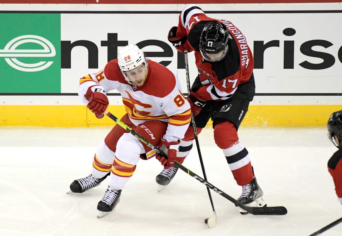 Calgary Flames left wing Andrew Mangiapane (88) and New Jersey Devils center Yegor Sharangovich (17) battle for the puck during the third period of an NHL hockey game Tuesday, Oct. 26, 2021, in Newark, N.J. The Flames won 5-3.