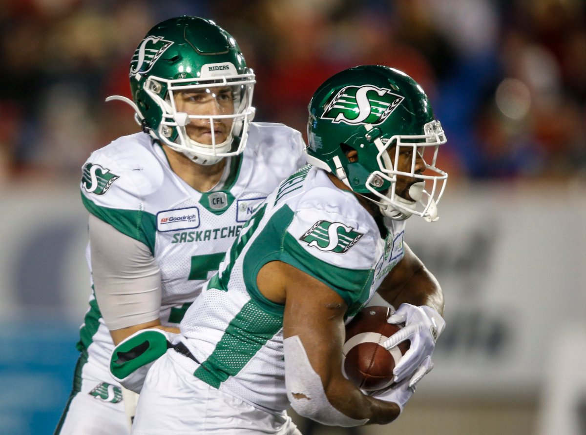 Saskatchewan Roughriders quarterback Cody Fajardo, left, hands the ball off to William Powell during second half CFL football action against the Calgary Stampeders in Calgary, Oct. 11, 2019.