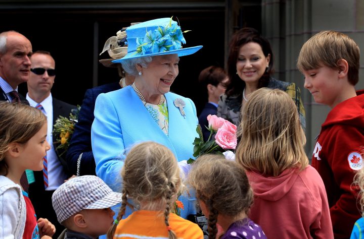 Queen Elizabeth II is given flowers by children as she visits the Canadian Museum of Nature on June 30, 2010 in Ottawa.