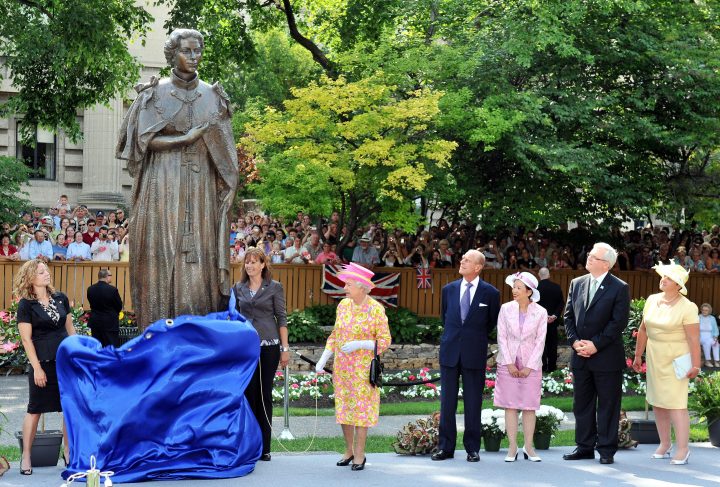 Queen Elizabeth II (C), beside Prince Philip, Duke of Edinburgh, unveils a statue of herself in the garden of Government House on July 3, 2010 in Winnipeg.