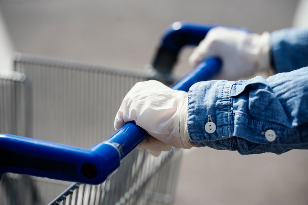 Woman with empty shopping cart wearing protective surgical masks and gloves.