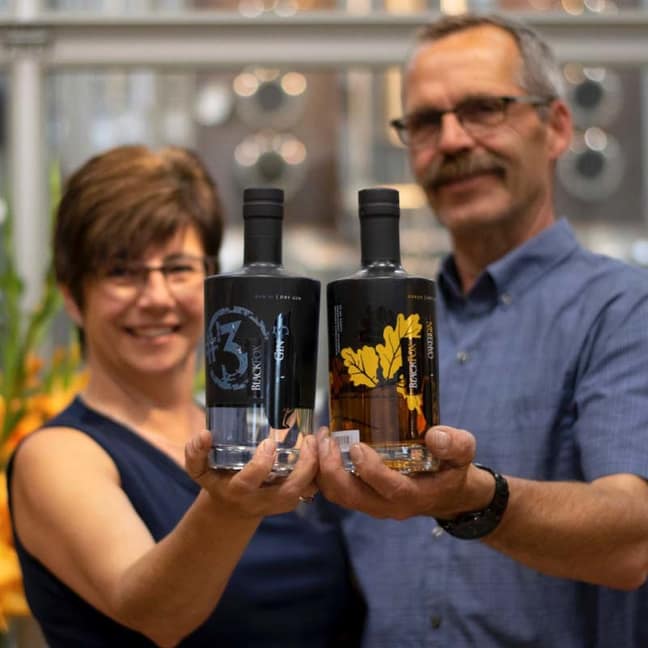 Owners of Black Fox Farm and Distillery, Barb Cote and John Cote holding up their spirits. 