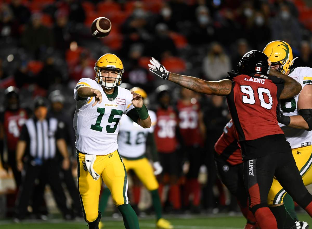 Edmonton Elks quarterback Taylor Cornelius (15) throws the ball past the arm of Ottawa Redblacks defensive lineman Cleyon Laing (90) during first half CFL football action in Ottawa on Tuesday, Sept. 28, 2021.