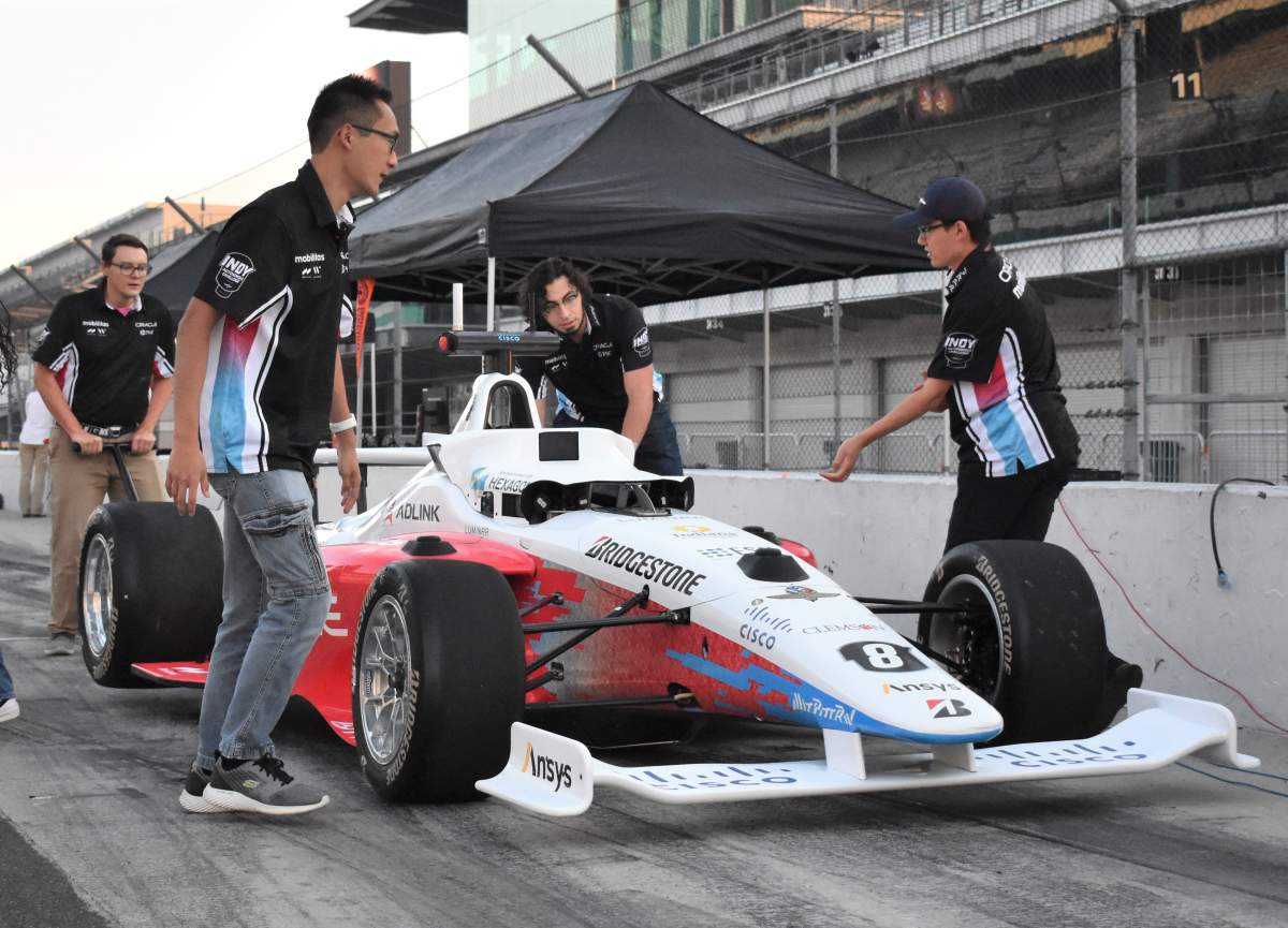 Waterloo students Brian Mao (front left) and Ben Zhang (front right) work with teammates during testing of their autonomous car at the Indy speedway.