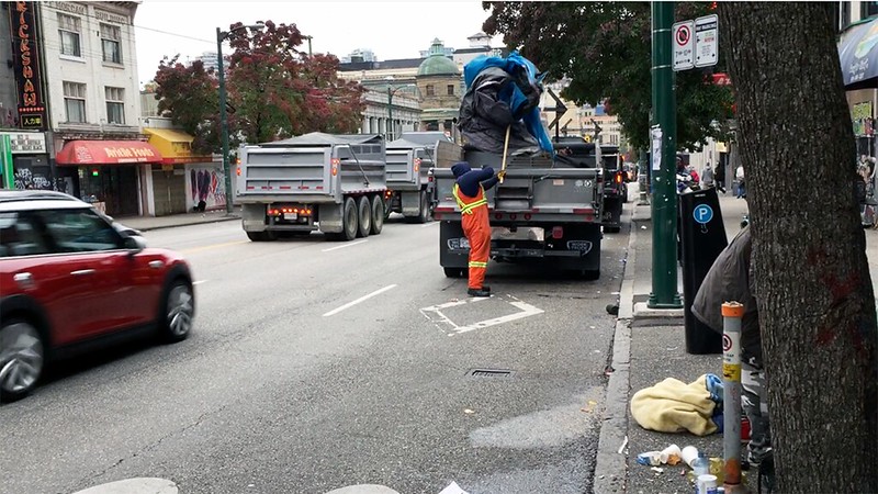 A city worker removes a tent from the sidewalk in Vancouver's Downtown Eastside.