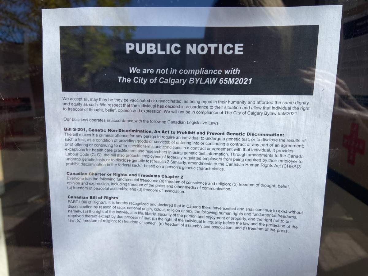 A sign at Without Papers Pizza in Inglewood states: “We are not in compliance with the City of Calgary bylaw 65M2021.”