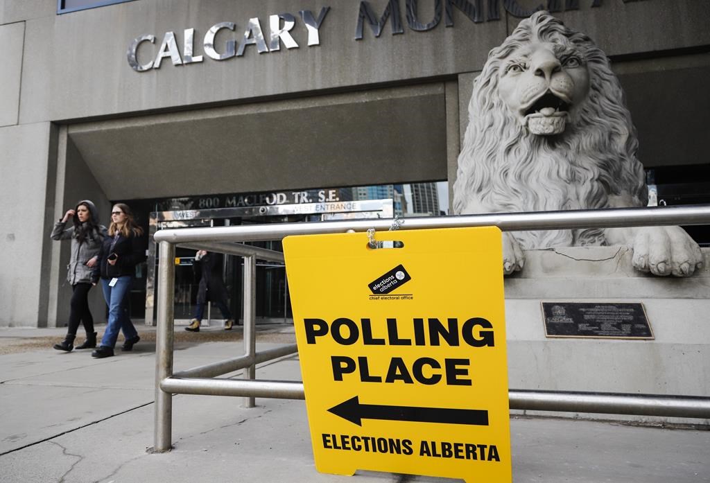 FILE: Pedestrians walk past an advance polling station sign outside Calgary city hall on Friday, April 12, 2019. 