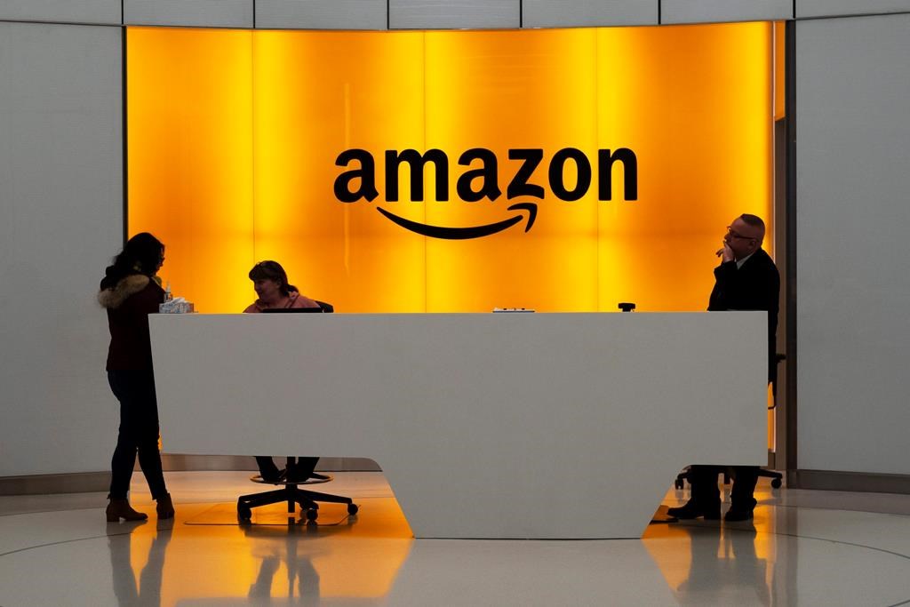 People stand in the lobby for Amazon offices in New York, Feb. 14, 2019. Amazon says it plans to open a second cloud-computing server hub in Canada in late 2023 that will mean billions of dollars of investments in the coming years. THE CANADIAN PRESS/AP-Mark Lennihan.