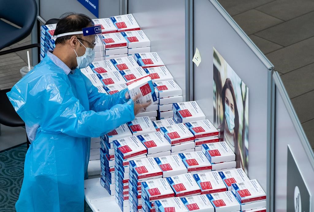 A worker picks up a COVID-19 self collection test kit which are given to arriving international passengers at Vancouver International Airport, in Richmond, B.C., on July 30, 2021.