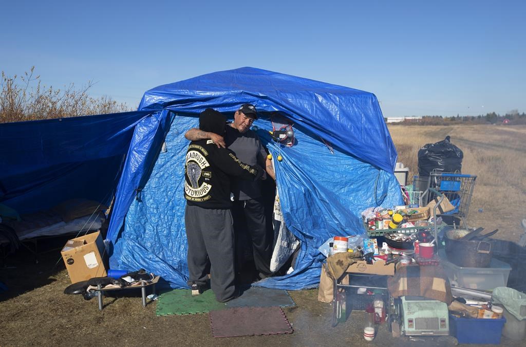 Alvin Johnson hugs another resident at a homeless camp on the outskirts of Wetaskiwin, Alta.