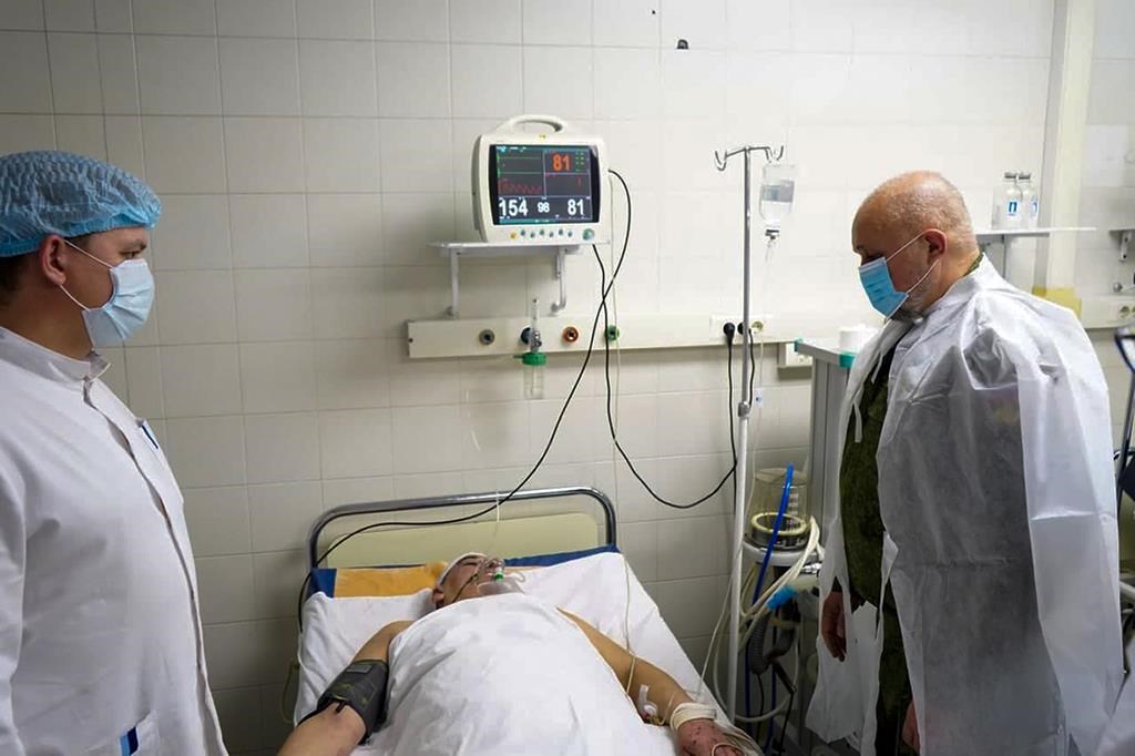 In this photo provided by the Governor of Kemerovo Region Press Office, Kemerovo Governor Sergei Tsivilyov, right, visits a wounded miner after an the accident at the Listvyazhnaya coal mine at the Kuzbass Clinical Center for the Protection of Miners' Health in Leninsk-Kuznetsky about 100 km (62 mies) of the Siberian city of Kemerovo, about 3,000 kilometres (1,900 miles) east of Moscow, Russia, Thursday, Nov. 25, 2021.