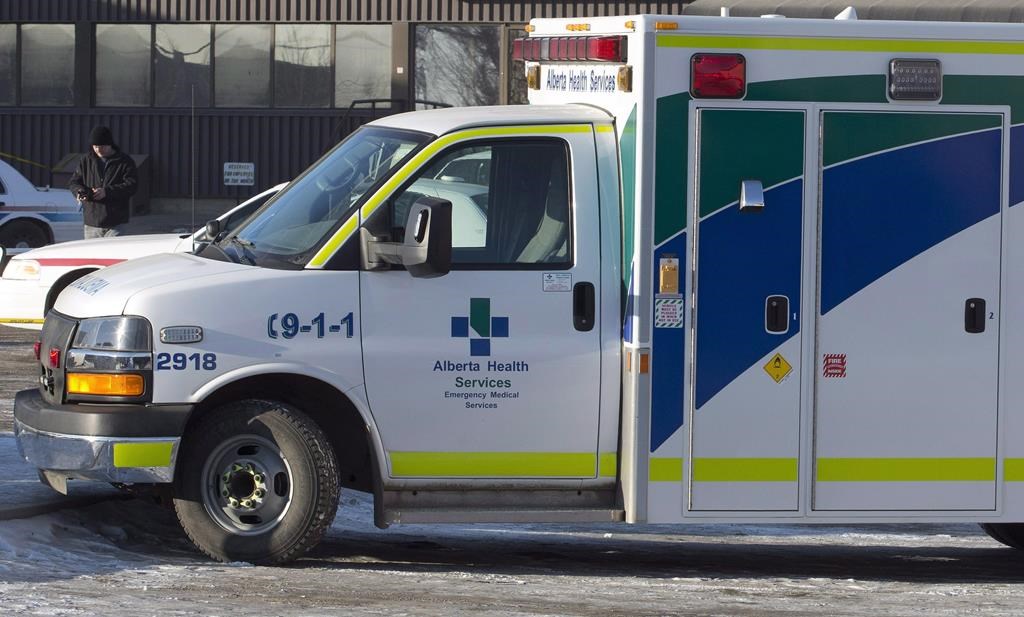 An ambulance waits at the scene as police investigate at a warehouse in Edmonton, on Friday, Feb. 28, 2014. Alberta's ombudsman says she doesn't have the power to investigate a complaint about the decision to consolidate ambulance emergency dispatch services in the province. THE CANADIAN PRESS/Jason Franson.