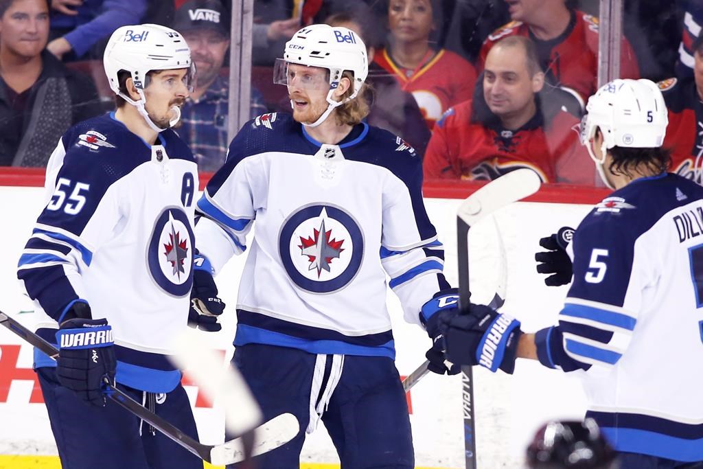 The Winnipeg Jets’ Kyle Connor, centre, celebrates his goal against the Calgary Flames with Mark Scheifele, left, and Brenden Dillon during third-period NHL hockey action in Calgary, Saturday, Nov. 27, 2021. THE CANADIAN PRESS/Larry Mac Dougal