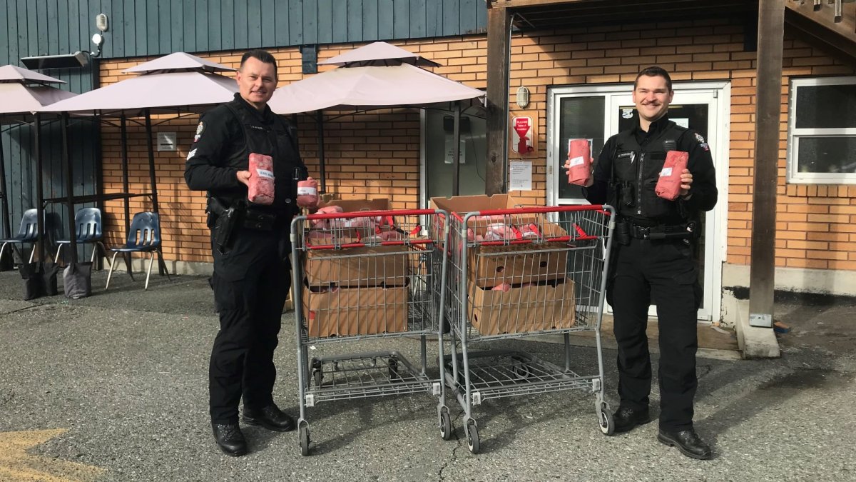 Two B.C. Conservation Officer Service members hold cut and wrapped moose meat before donating it to a food bank in Abbotsford.