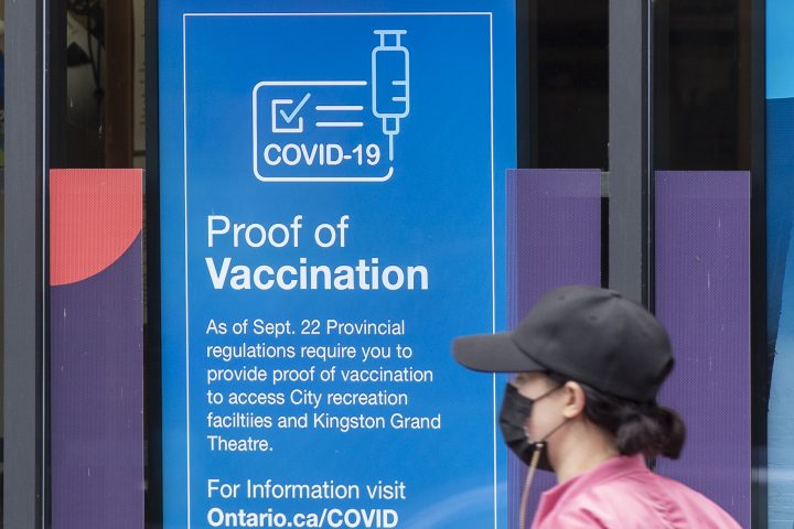 A person wears a mask to protect from the COVID-19 while walking past information about vaccination proof in Kingston, Ontario on Thursday September 23, 2021.