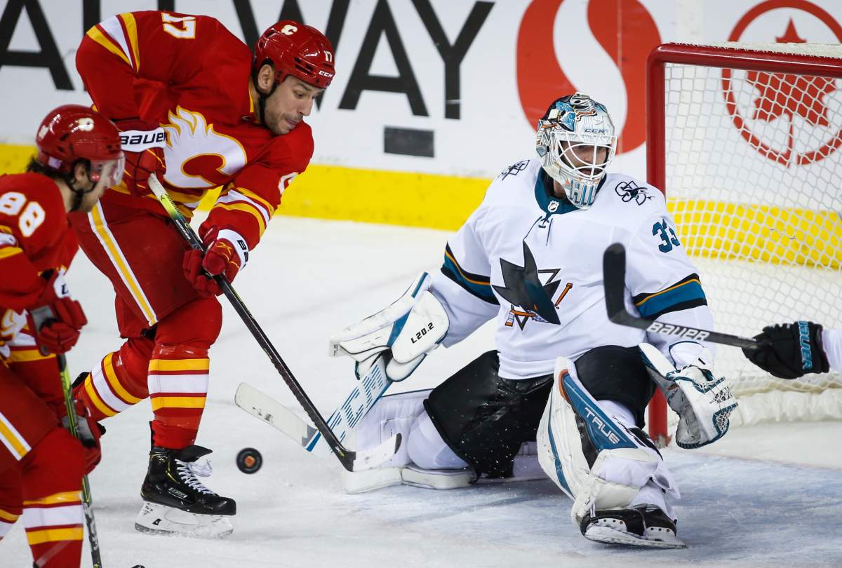 San Jose Sharks goalie Adin Hill, right, looks for the puck as Calgary Flames’ Milan Lucic scrambles for the rebound during second period NHL hockey action in Calgary, Tuesday, Nov. 9, 2021.