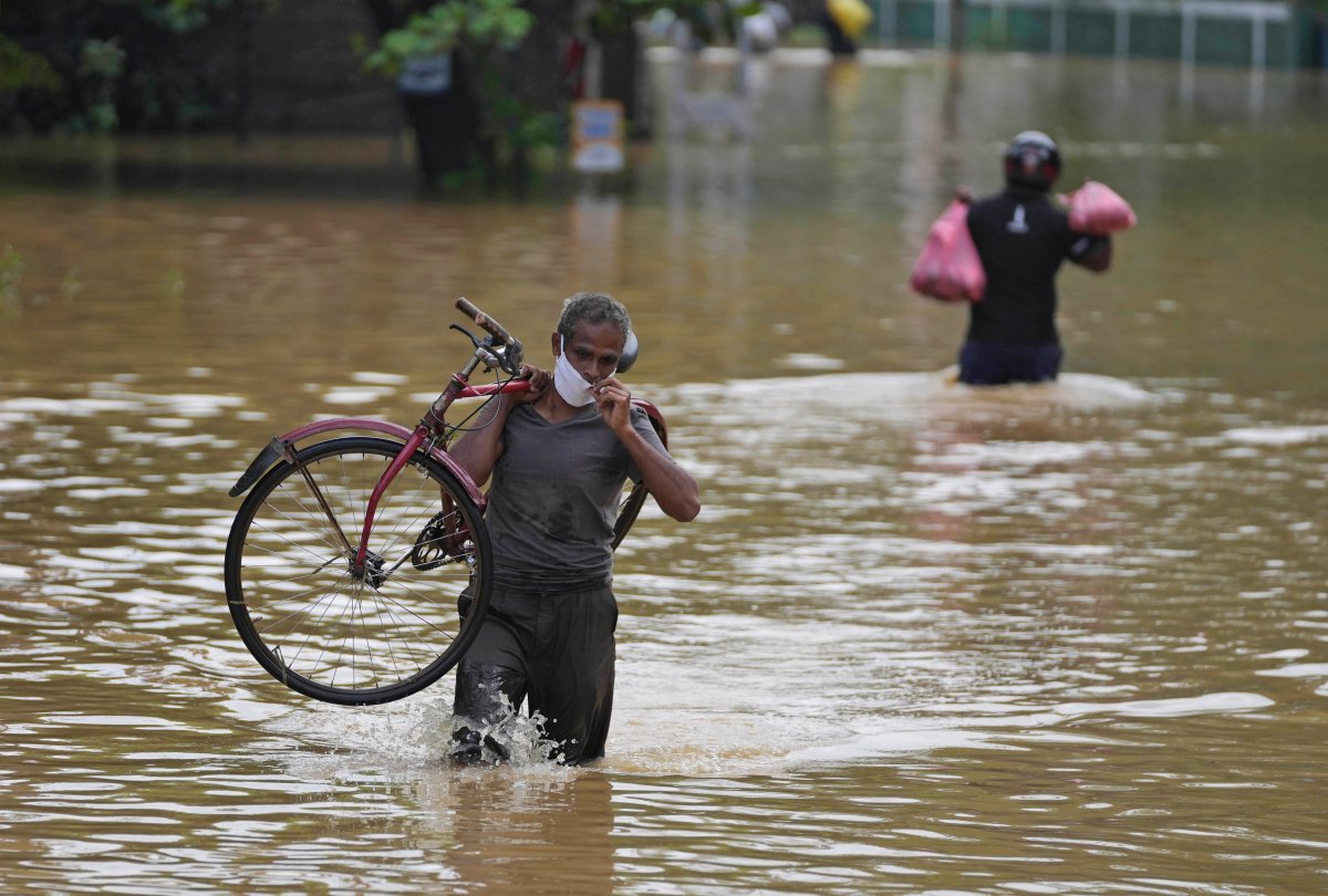 A Sri Lankan man wades through a flooded road carrying his bicycle in Kochchikade, about 30 kilometres north of Colombo, Sri Lanka, Wednesday, Nov. 10, 2021. At least 16 people have died in floods and mudslides in Sri Lanka following more than a week of heavy rain, officials said Wednesday. (AP Photo/Eranga Jayawardena).