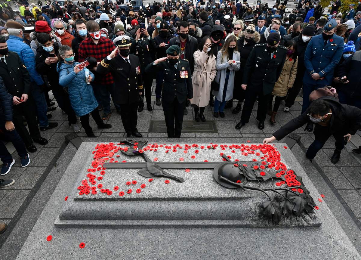 Canadian Forces members salute after placing their poppies on the Tomb of the Unknown Soldier at the National War Memorial following the National Remembrance Day Ceremony in Ottawa, on Thursday, Nov. 11, 2021.