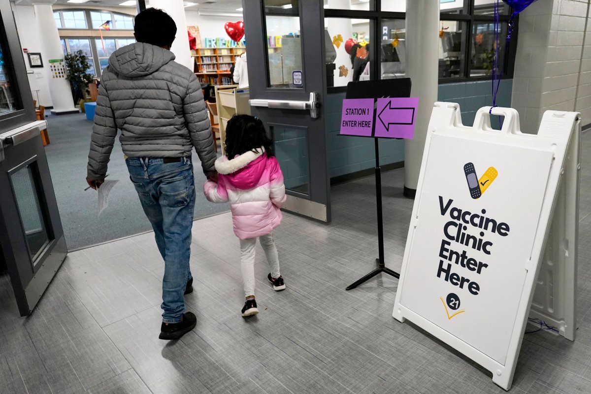 An information sign is displayed as a child arrives with her parent to receive the Pfizer COVID-19 vaccine for children at an Illinois clinic.
