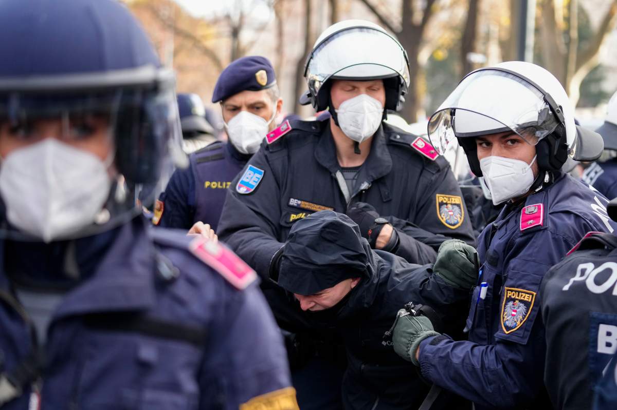 Police officers detain a man during a demonstration against measures to battle the coronavirus pandemic in Vienna, Austria, Saturday, Nov.20, 2021. (AP Photo/Florian Schroetter)