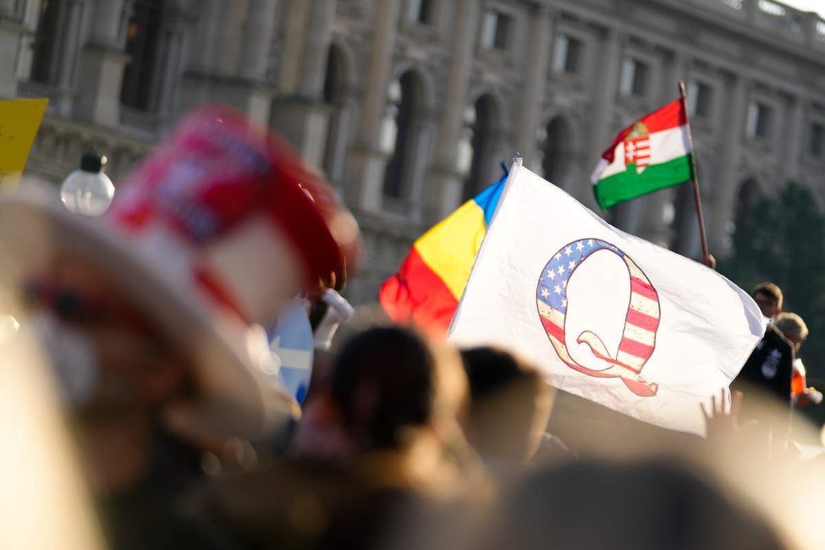 Protestors with a flag showing a ‘Q’ attend a demonstration against measures to battle the coronavirus pandemic in Vienna, Austria, Saturday, Nov. 20, 2021. (AP Photo/Florian Schroetter)
